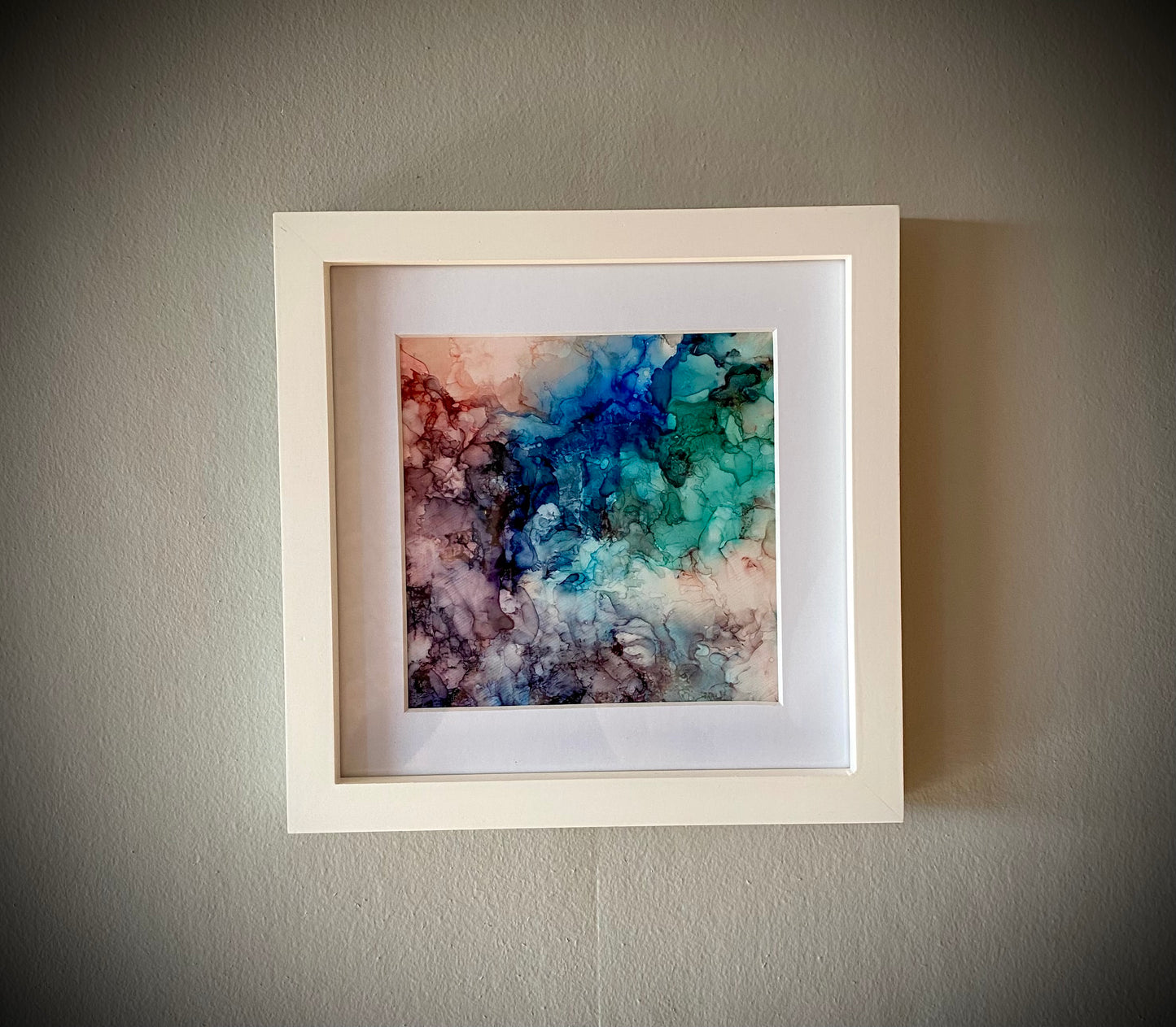 Tavla i alkoholbläck. Vit ram 22x22 cm. Målningen med passepartout 14x14 cm.